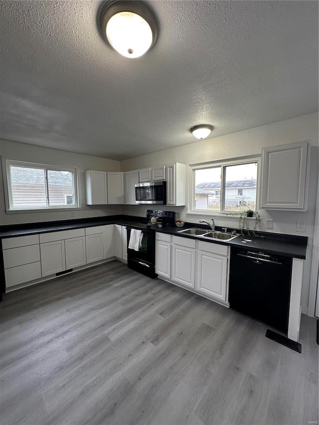 kitchen featuring sink, black appliances, a textured ceiling, white cabinets, and light wood-type flooring