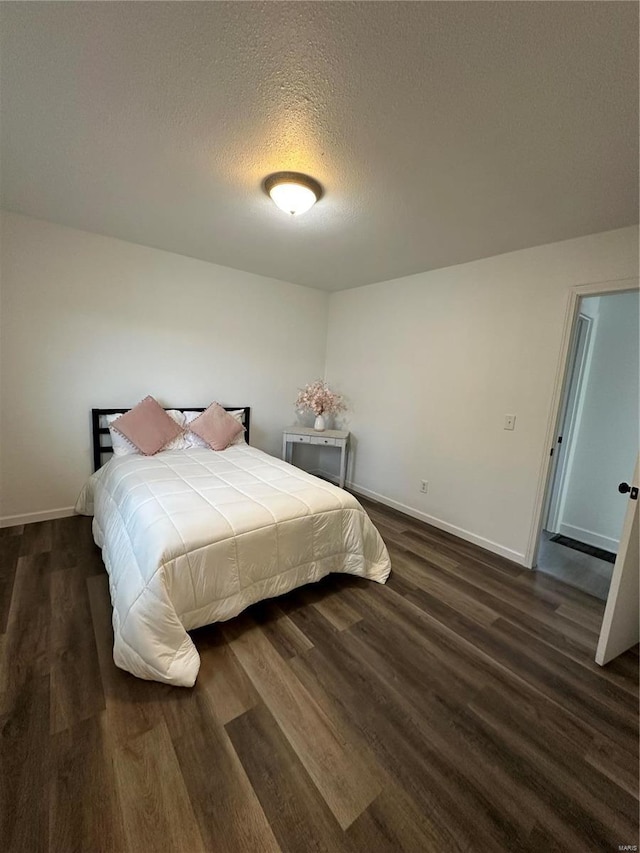 bedroom with dark hardwood / wood-style floors and a textured ceiling