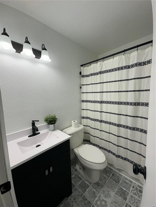 bathroom with walk in shower, vanity, toilet, and a textured ceiling