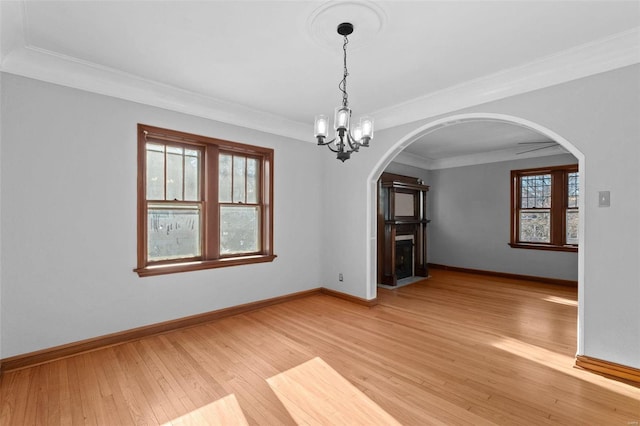 unfurnished dining area featuring ornamental molding, a healthy amount of sunlight, a chandelier, and light hardwood / wood-style floors