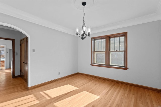 unfurnished room with an inviting chandelier, ornamental molding, and light hardwood / wood-style flooring