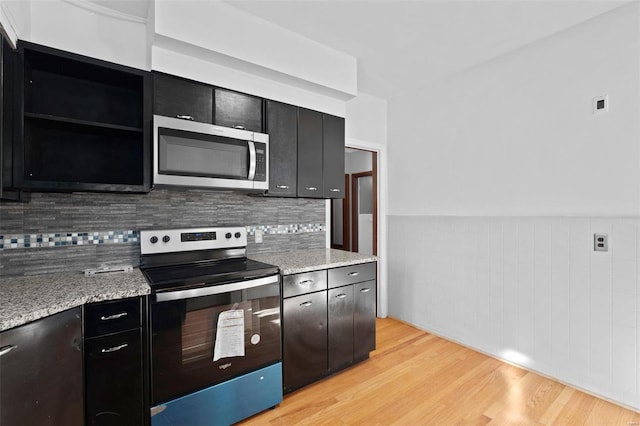 kitchen with light stone counters, stainless steel appliances, light hardwood / wood-style flooring, and backsplash