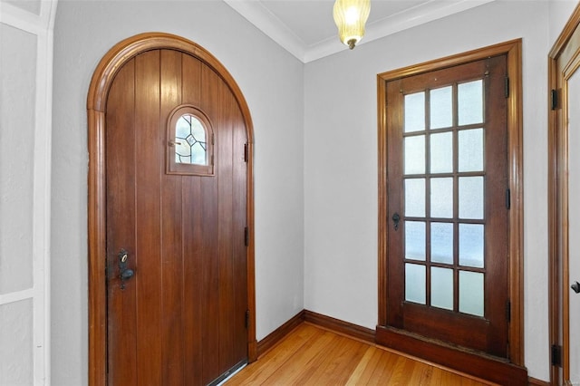 foyer entrance with ornamental molding, a wealth of natural light, and light hardwood / wood-style flooring