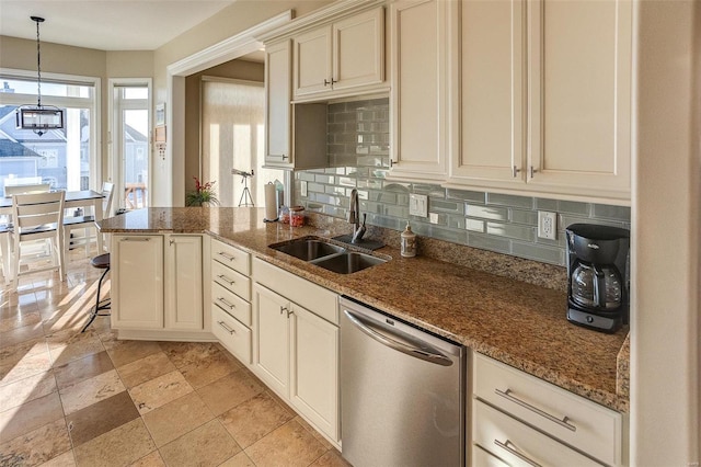 kitchen with tasteful backsplash, dark stone counters, sink, cream cabinetry, and dishwasher