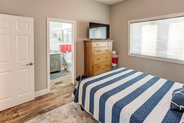 bedroom with ensuite bath and light hardwood / wood-style floors