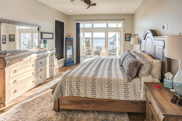 bedroom with access to exterior, light hardwood / wood-style floors, and a water view