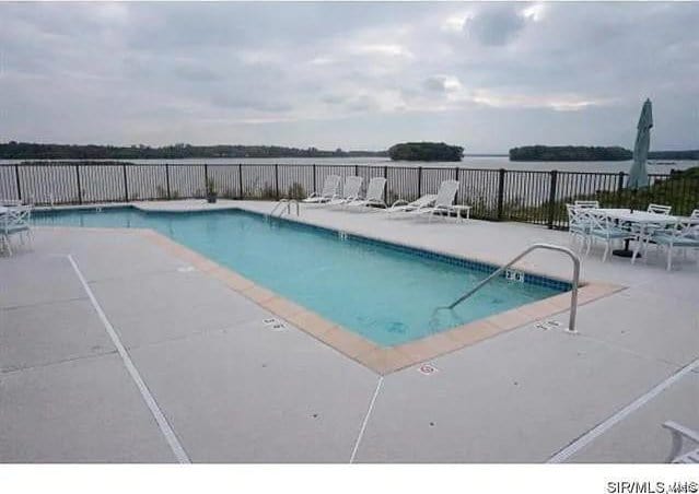 view of swimming pool with a patio area and a water view