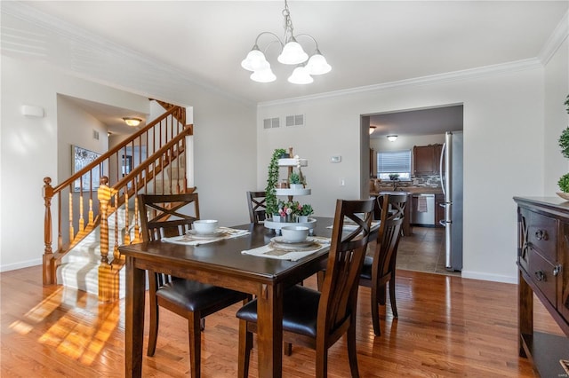 dining space with an inviting chandelier, hardwood / wood-style floors, and ornamental molding