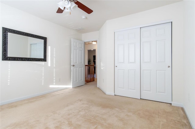 unfurnished bedroom featuring light colored carpet, ceiling fan, and a closet