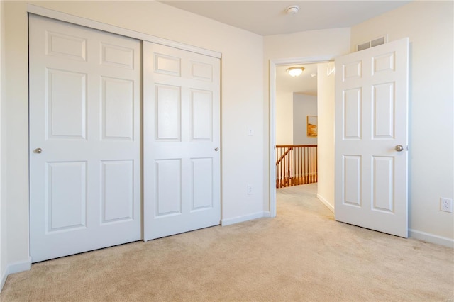 unfurnished bedroom with light carpet and a closet