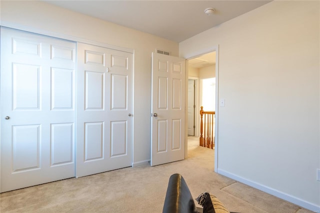 unfurnished bedroom with light colored carpet and a closet