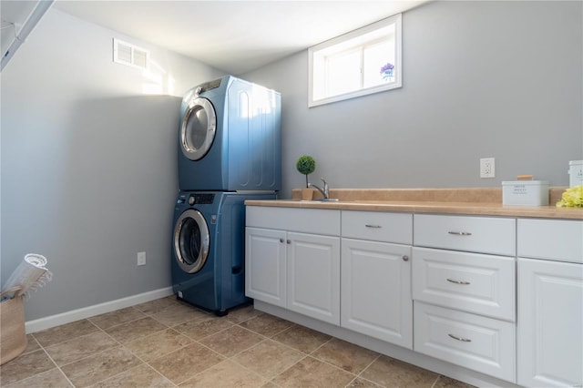 laundry room with cabinets, stacked washing maching and dryer, and sink