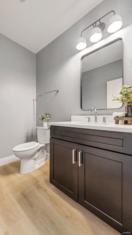 bathroom featuring wood-type flooring, vanity, and toilet