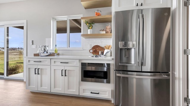 kitchen featuring white cabinets, light hardwood / wood-style flooring, stainless steel appliances, and tasteful backsplash