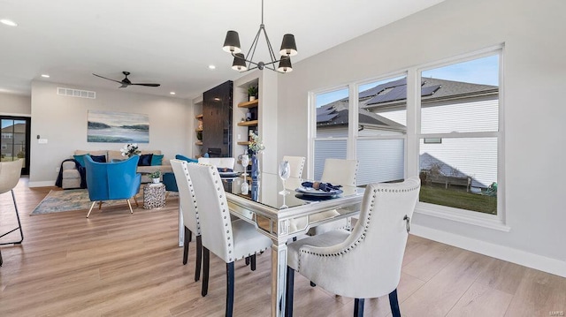 dining space with light hardwood / wood-style flooring and ceiling fan with notable chandelier