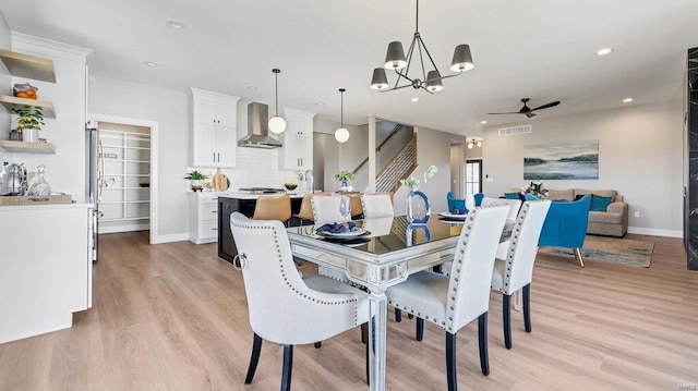 dining space with light hardwood / wood-style flooring and ceiling fan with notable chandelier