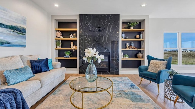 living room with a fireplace, wood-type flooring, and built in features