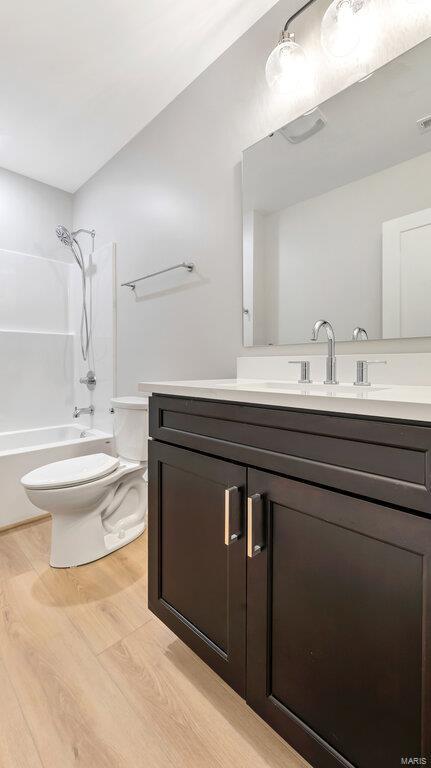 full bathroom featuring washtub / shower combination, hardwood / wood-style floors, vanity, and toilet