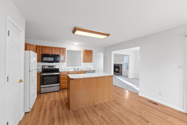 kitchen with white fridge, a center island, stainless steel range with electric cooktop, and light wood-type flooring