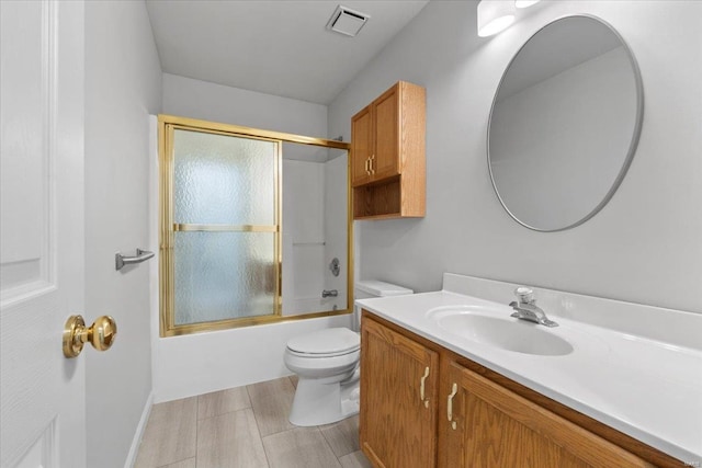 full bathroom featuring vanity, combined bath / shower with glass door, and toilet