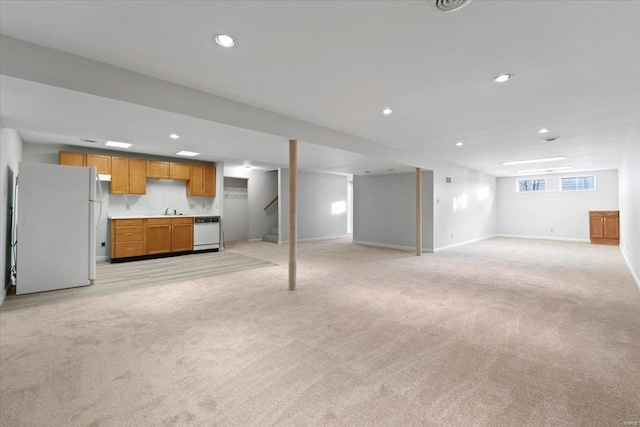 basement with white refrigerator, sink, and light carpet