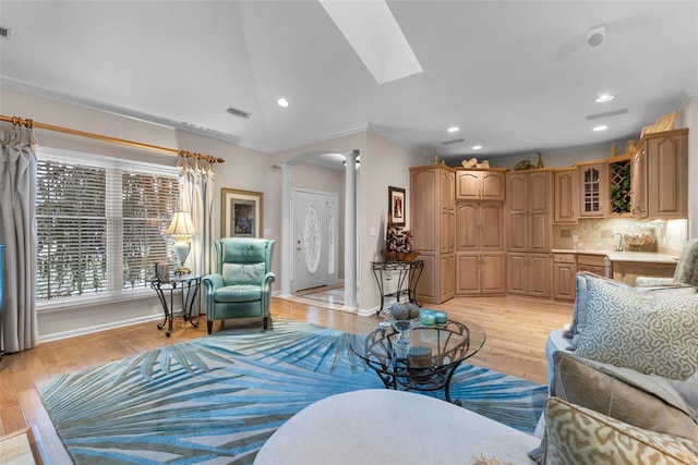 living room featuring vaulted ceiling, light hardwood / wood-style flooring, ornate columns, and crown molding