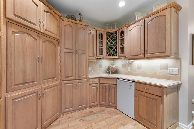 kitchen featuring backsplash, sink, crown molding, light hardwood / wood-style flooring, and dishwashing machine