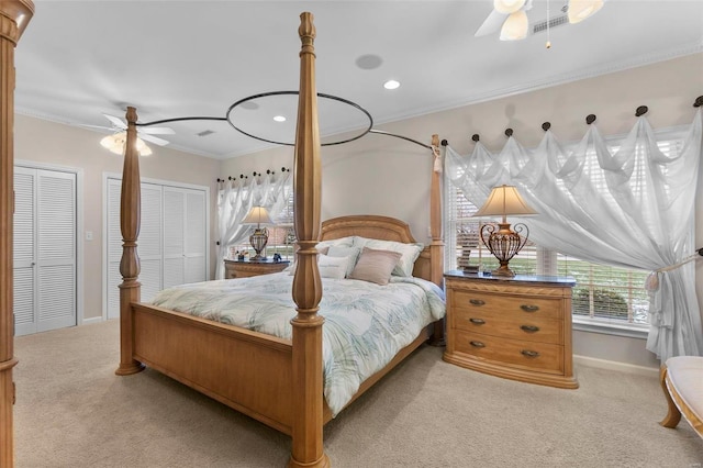 carpeted bedroom featuring ceiling fan, two closets, and ornamental molding