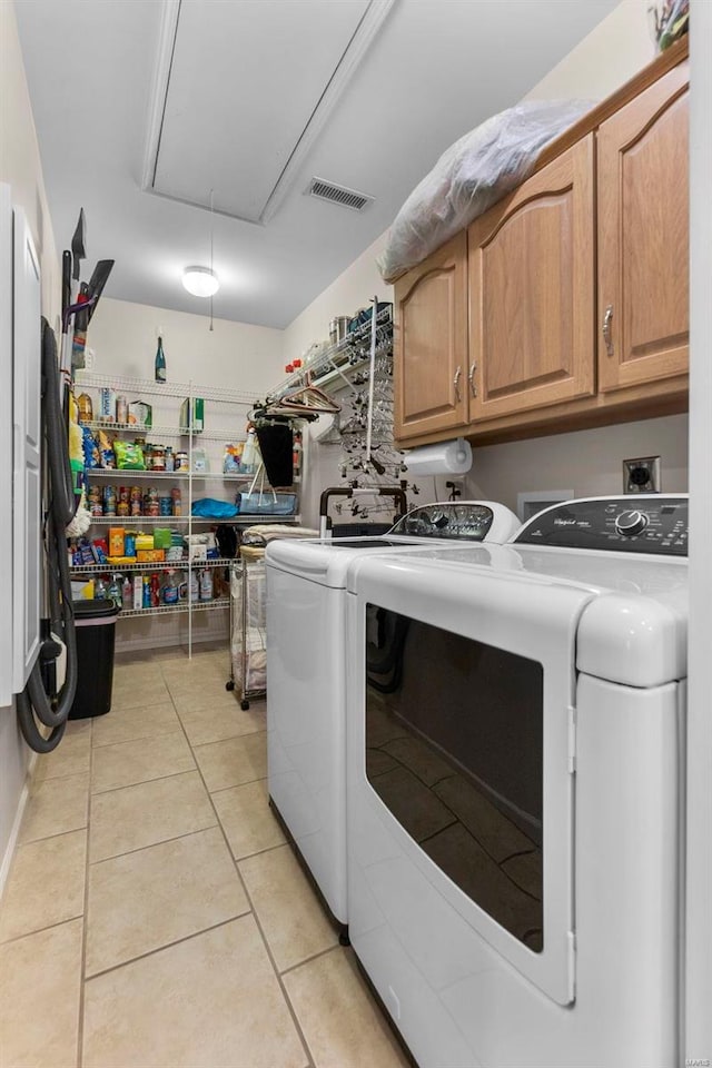 laundry area featuring cabinets, washer and clothes dryer, and light tile patterned flooring