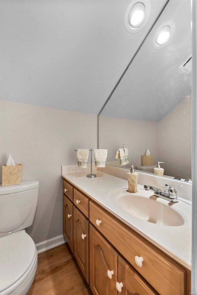 bathroom with vanity, hardwood / wood-style flooring, toilet, and vaulted ceiling