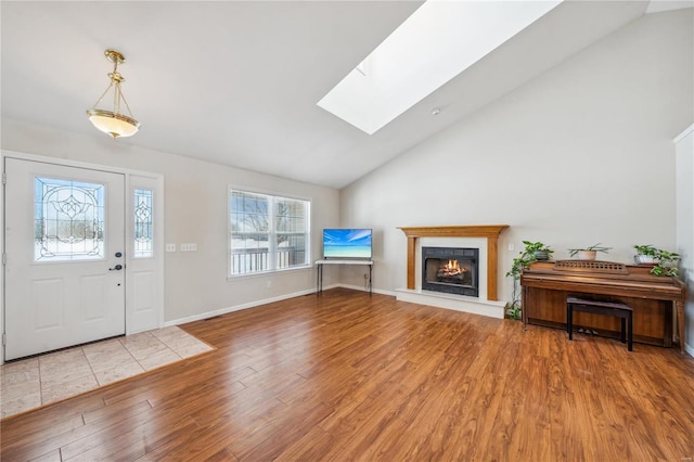 foyer featuring vaulted ceiling with skylight, wood-type flooring, and a tile fireplace