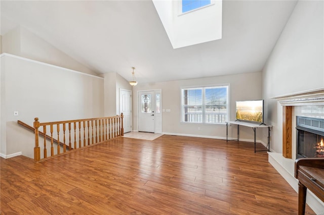 foyer entrance with lofted ceiling with skylight and hardwood / wood-style floors