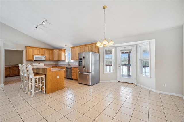 kitchen featuring vaulted ceiling, a kitchen island, a breakfast bar, appliances with stainless steel finishes, and light tile patterned floors