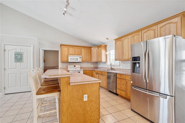 kitchen with appliances with stainless steel finishes, light tile patterned flooring, vaulted ceiling, a kitchen island, and sink