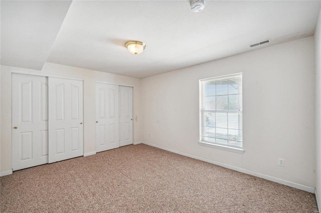 unfurnished bedroom with two closets and carpet flooring