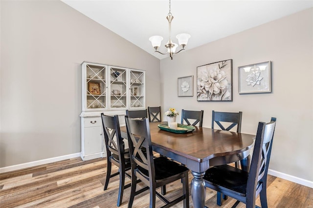 dining space with lofted ceiling, a chandelier, and hardwood / wood-style flooring