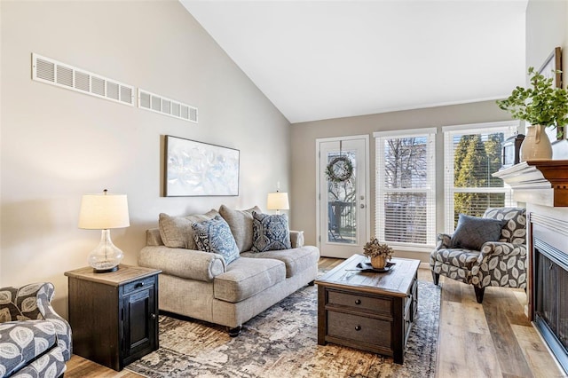 living room with high vaulted ceiling and light hardwood / wood-style flooring