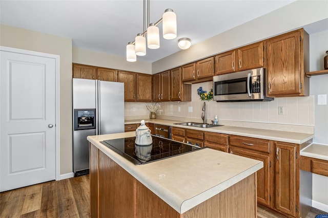 kitchen with stainless steel appliances, hanging light fixtures, dark wood-type flooring, sink, and backsplash