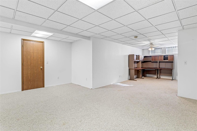 basement with ceiling fan, a paneled ceiling, and carpet