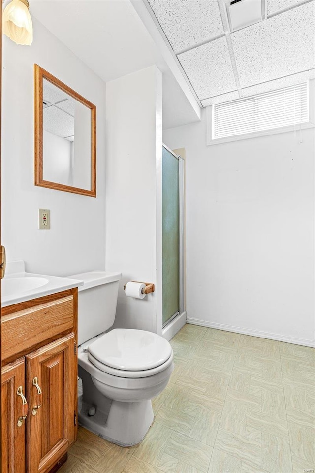 bathroom featuring a paneled ceiling, vanity, a shower with shower door, and toilet