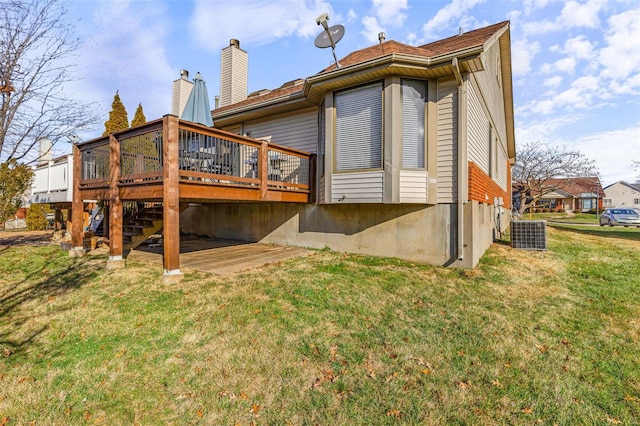 rear view of property featuring central AC, a deck, and a lawn