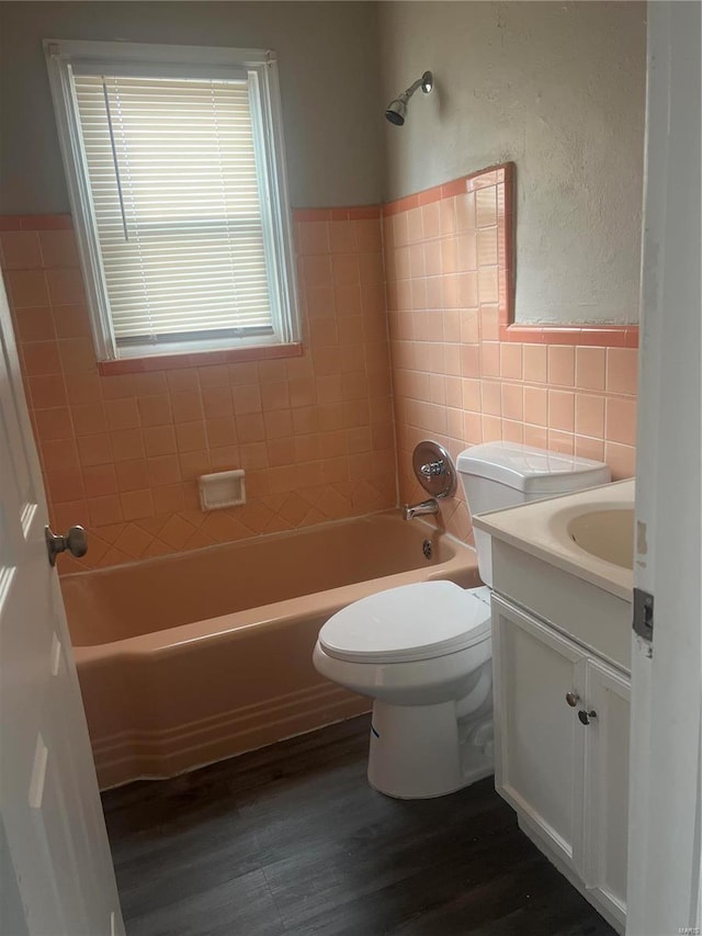 full bathroom with vanity, tiled shower / bath combo, toilet, tile walls, and wood-type flooring