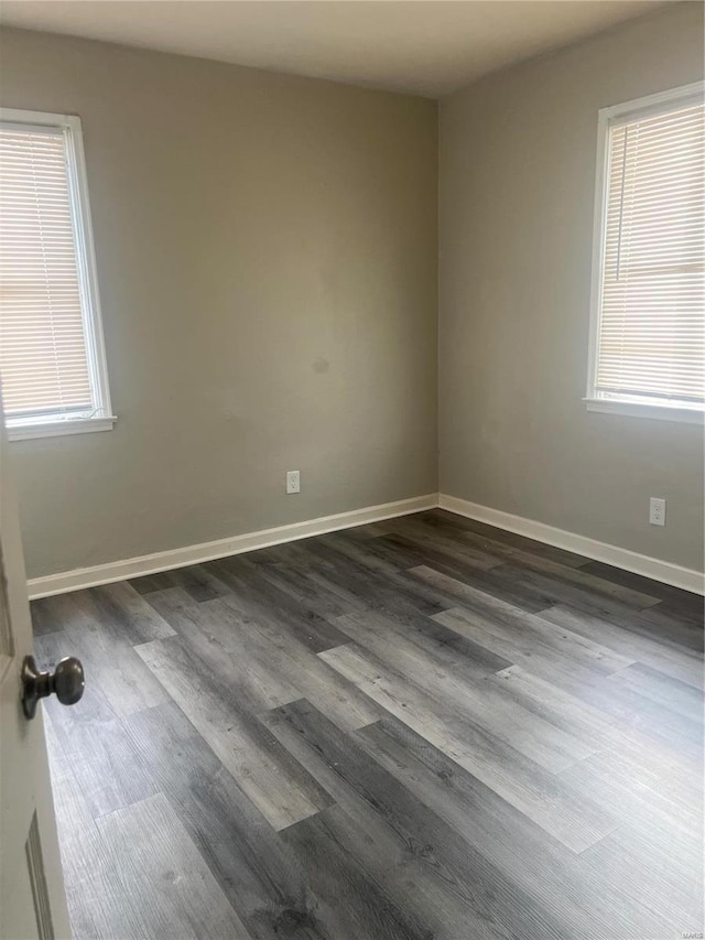 empty room featuring a healthy amount of sunlight and dark wood-type flooring