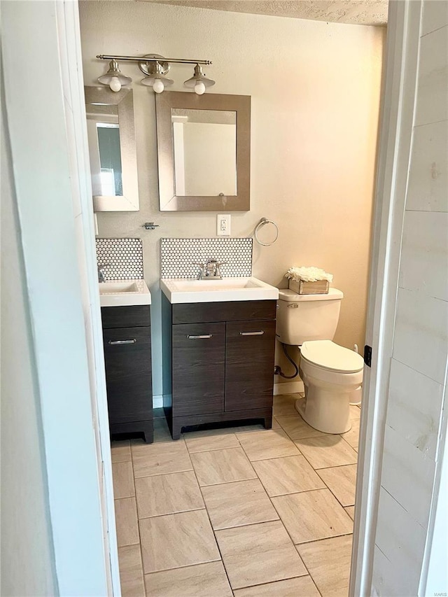 bathroom featuring tasteful backsplash, tile patterned floors, vanity, and toilet