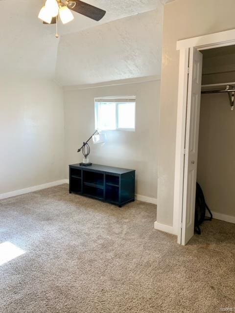 unfurnished bedroom featuring carpet, a closet, vaulted ceiling, and ceiling fan