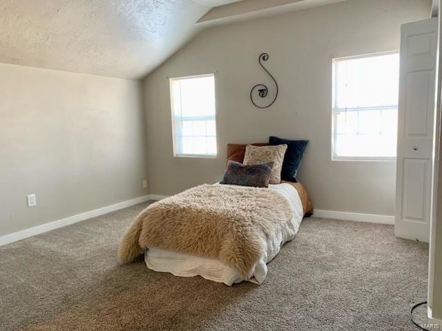 bedroom with light colored carpet, a textured ceiling, and vaulted ceiling