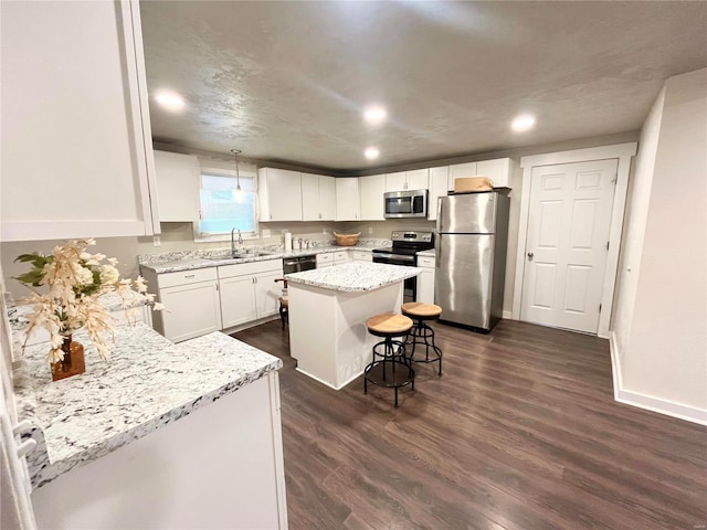 kitchen featuring a center island, white cabinets, sink, appliances with stainless steel finishes, and a breakfast bar area