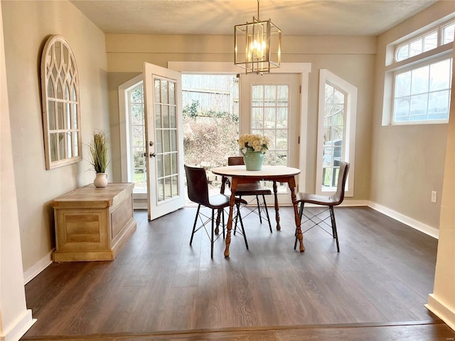 dining space featuring plenty of natural light, french doors, dark wood-type flooring, and a chandelier