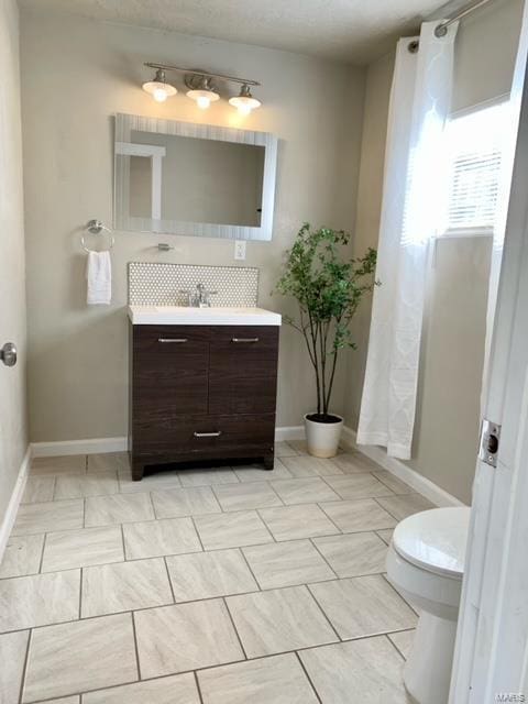 bathroom with backsplash, vanity, and toilet