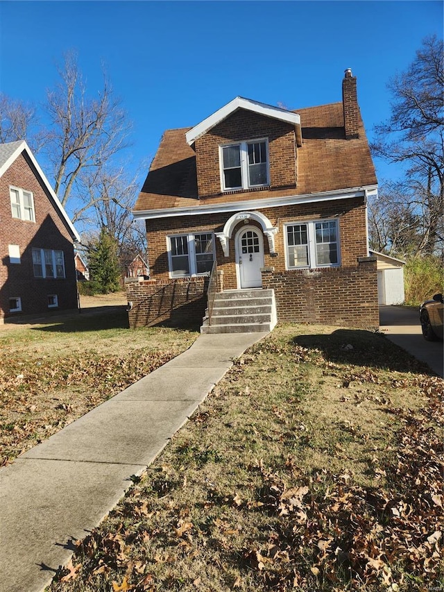 view of front facade with a front yard, a garage, and an outdoor structure